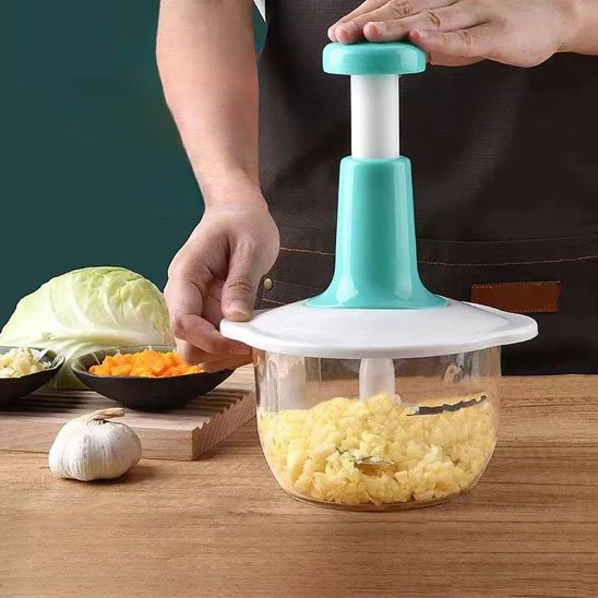 Hachoir manuel à pression avec ail et chou sur une planche en bois