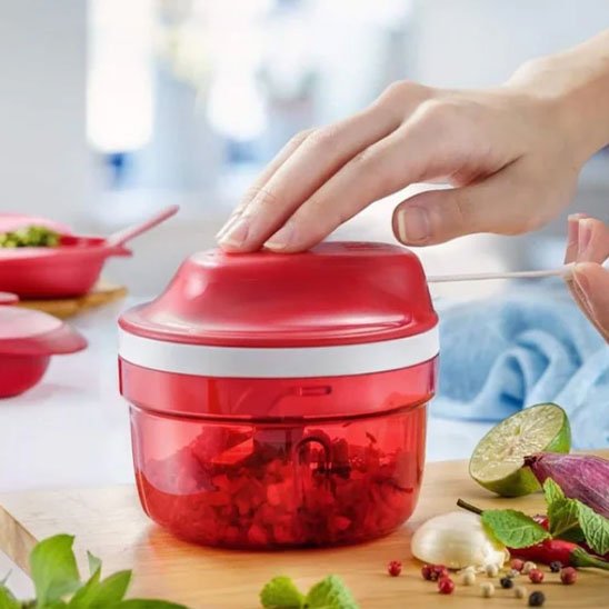 hachoir manuel rouge avec main femme